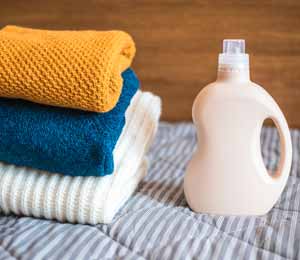 Wollwaschmittel: Wollpullover liegen neben Waschmittel