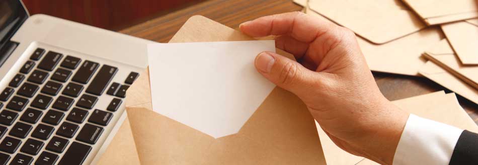 Briefmarken online kaufen: Ein Mann tütet ein Schreiben in einen Umschlag ein