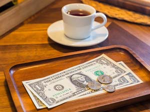 Trinkgeld in den USA: Eine Kaffeetasse mit Geld steht auf dem Tisch