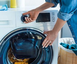 Waschmaschine kaufen: Eine Frau schließt eine Waschmaschine