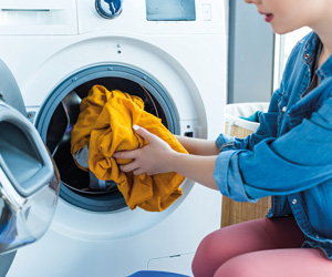 Waschmaschine kaufen: Eine Frau belädt eine Waschmaschine