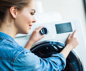 Waschmaschine kaufen: Eine Frau bedient einen Waschtrockner