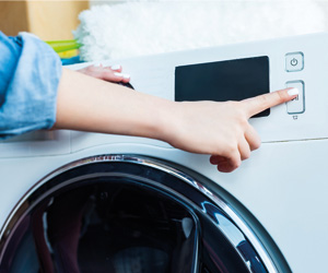 Waschmaschine kaufen: Eine Frau bedient einen Waschtrockner