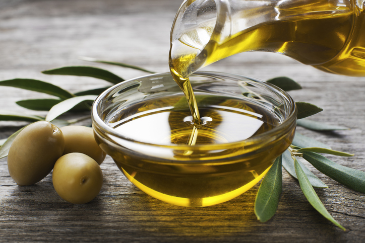 Olivenöl wird aus einer Karaffe in eine Schale gegossen