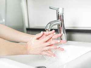 Hände waschen: Eine Frau reinigt die Hände unter laufendem Wasser