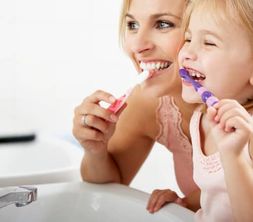 Weiße Zähne: Eine Mutter zeigt ihrer Tochter, wie man die Zähne richtig putzt