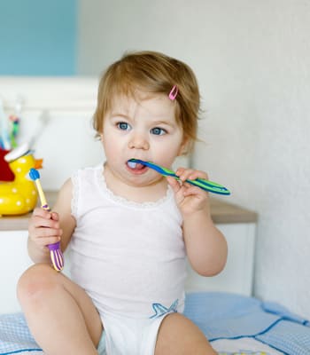 Richtige Zahnpasta: Ein Kleinkind putzt sich mit Zahnpasta für Kinder die Zähne. Für die Kleinsten gibt es dafür Baby Zahnpasta.