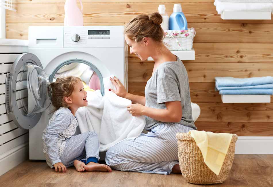 Eine Frau sitzt mit einem Kind vor einer Waschmaschine