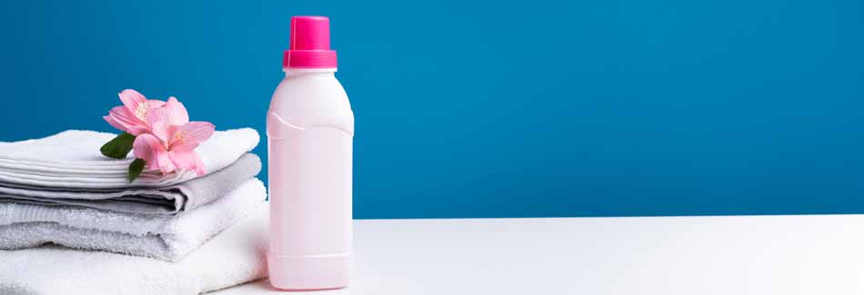 Flüssigwaschmittel: Wäsche liegt neben einer Flasche mit Waschmittel