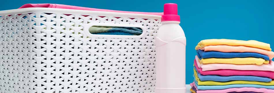 Flüssigwaschmittel: Wäsche liegt neben einem Wäschekorb