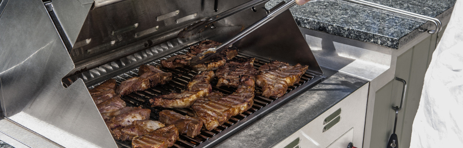 Fleisch liegt auf einem Grill mit Grillwagen: Hier lässt sich Grillzubehör perfekt aufbewahren