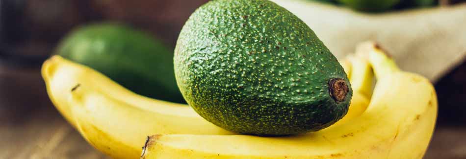 Reife von Obst erkennen: Eine Avocado liegt auf Bananen