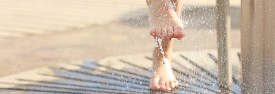 Geschwollene Beine im Sommer: Eine Frau duscht die Füße ab