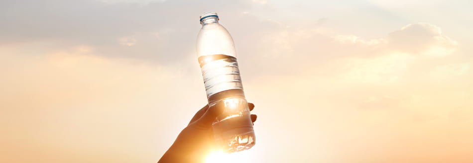 Regenwasser trinken: Jemand hält eine Flasche mit Wasser in Richtung Himmel
