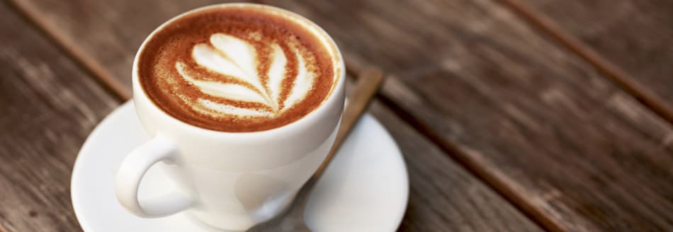 Eine Tasse Kaffee steht auf dunklem Holz