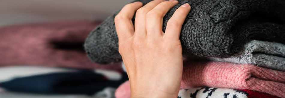 Mief im Kleiderschrank: Jemand nimmt einen Pullover aus dem Schrank