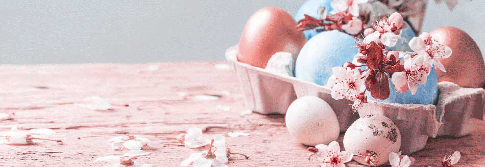 Osterdeko basteln: Bunte Eier liegen mit Frühlingspflanzen in einem Körbchen