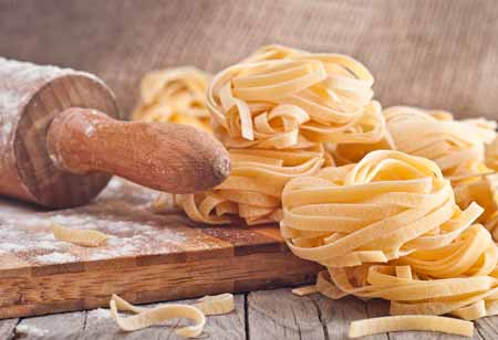 Pasta: Bandnudeln liegen neben einem Nudelholz