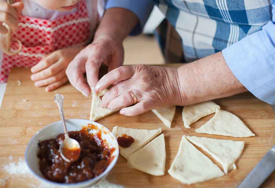 Oma Hildes Tipps: Eine ältere Frau hilft einem Kind beim Backen