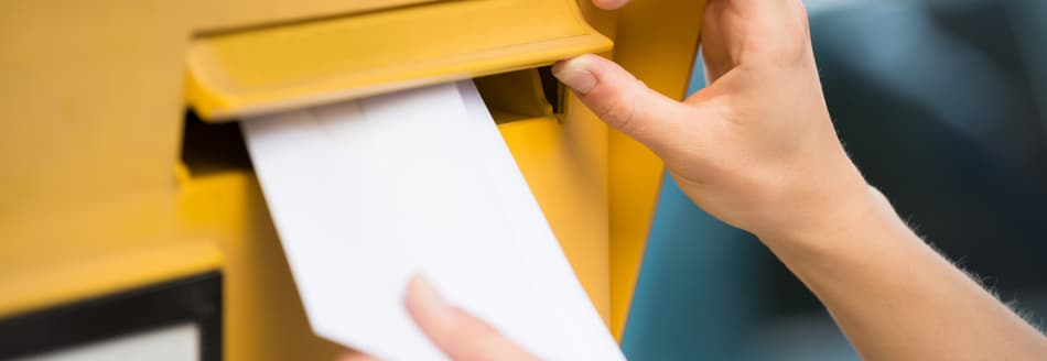 Was kostet ein Brief? Eine Frau wirft einen Umschlag in den Briefkasten