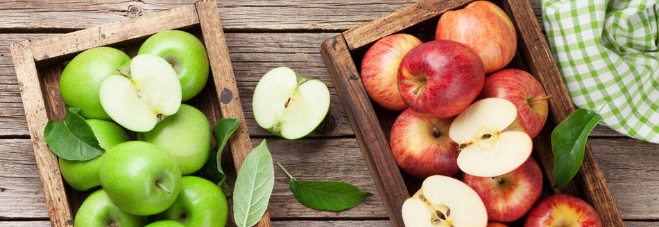 Vitamingehalt von Äpfeln: Grüne und rote Äpfel liegen in Holzkörben aufeinander