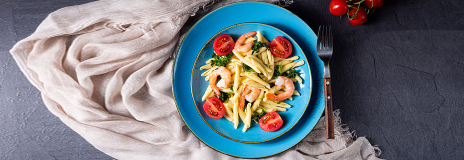 Lecker zubereitetes Gericht mit Strozzapreti, Garnelen und Tomaten