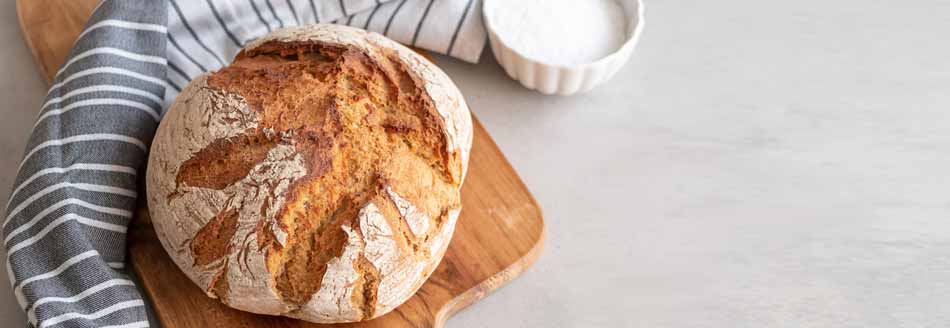 Kann man den Brotaufkleber mitessen? Ein frisches Brot liegt auf einem Holzbrett