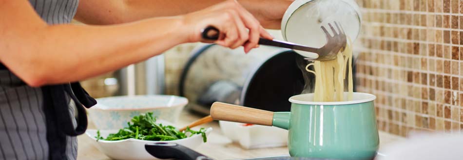 Strom sparen beim Kochen: Eine Frau kocht Nudeln