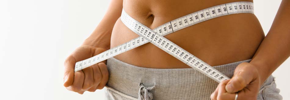 BMI Body-Mass-Index: Eine Frau misst den Taillenumfang