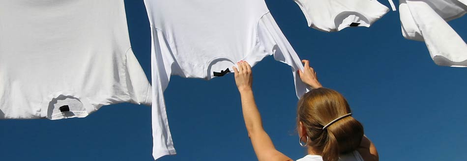 Schweißflecken entfernen: Eine Frau hängt Wäsche auf