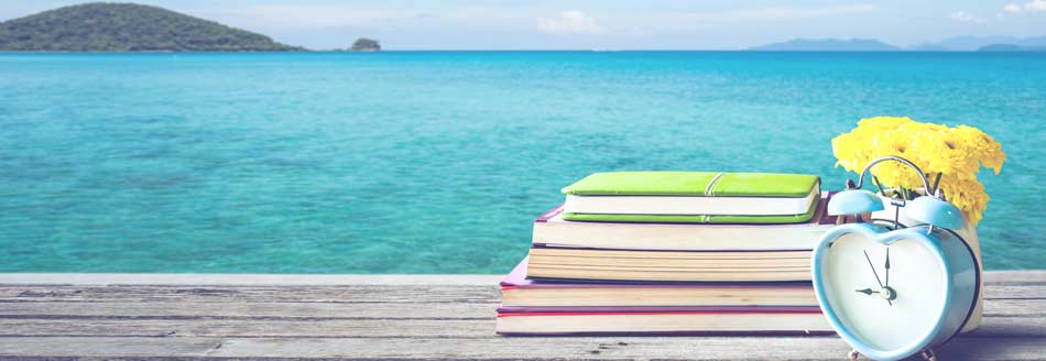 Last-Minute-Urlaub am Strand: Bücher und ein Wecker auf einem Steg