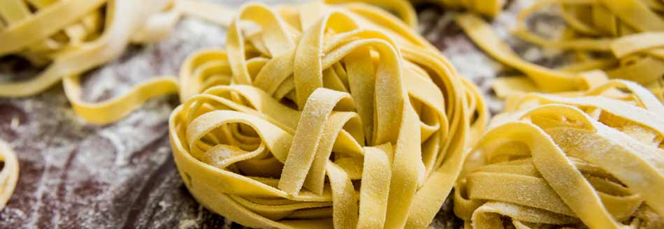 Tagliatelle mit Mehl auf Holz