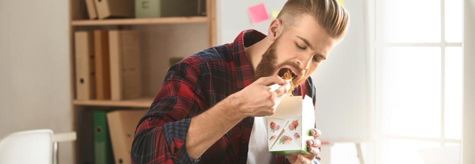 Schnell essen macht dick: Ein Mann isst am Arbeitsplatz