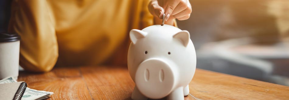 Neues rund ums Geld 2022: Eine Frau wirft eine Münze in ein Sparschwein