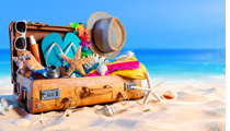 Ferien 2025: Ein vollgepackter Koffer steht geöffnet am Strand
