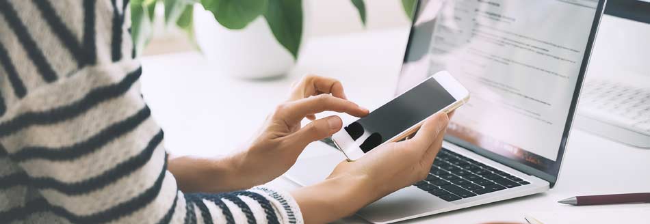 Eine Frau mit Smartphone am Schreibtisch