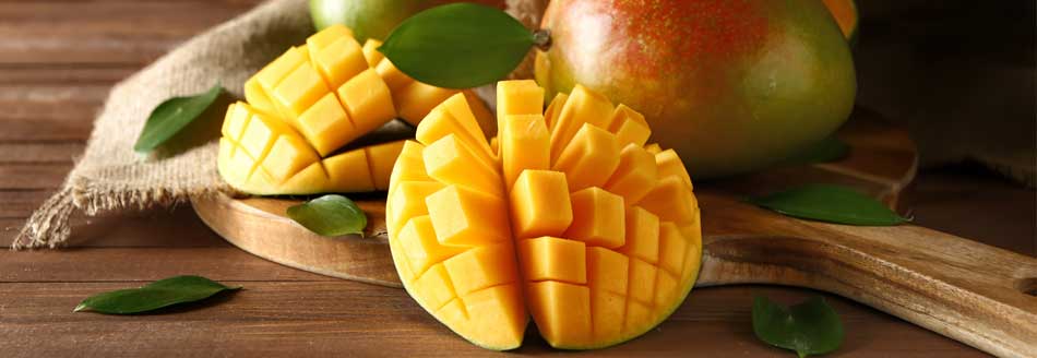 Eine aufgeschnittene Mango liegt neben einer ganzen Frucht