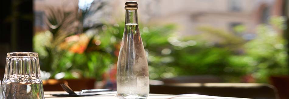 In einem Restaurant steht eine Flasche Mineralwasser auf dem Tisch