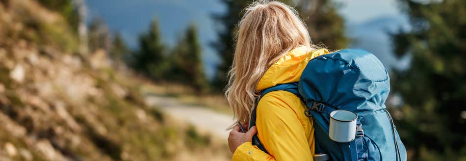 Eine Frau in einer quietschgelben Jacke steht in der Natur herum