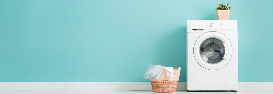 Eine Waschmaschine steht vor einer türkisfarbenen Wand.