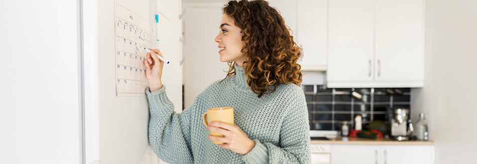 Feiertage 2029: Eine junge Frau notiert etwas in einem Wandkalender