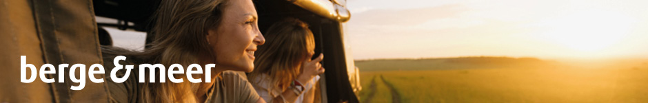 Zwei Personen schauen aus einem fahrenden Fahrzeug in eine sonnige Landschaft; Logo berge & meer