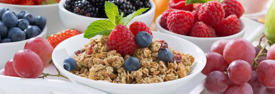 Ein gedeckter Frühstückstisch mit Müsli, Beeren und Trauben