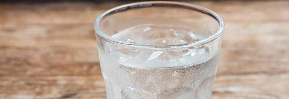 Stoffwechseldiät: Ein Glas mit kaltem Wasser steht auf einem Holztisch