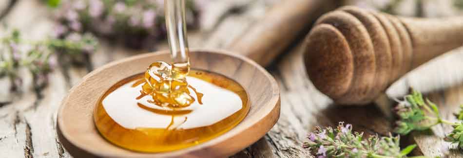 Hausmittel gegen Erkältung: Honig läuft in einen Holzlöffel