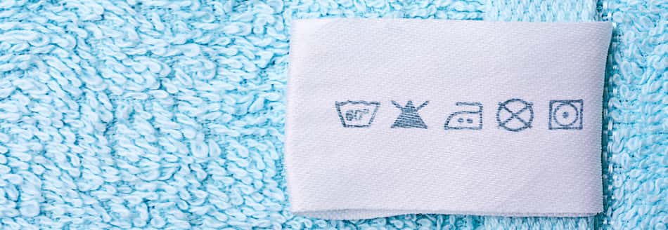 An einem blauen Handtuch ist ein Etikett mit Waschsymbolen angebracht