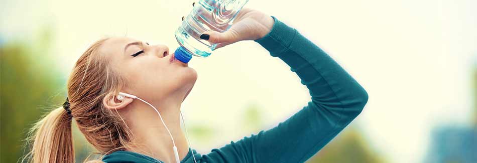 Joggen anfangen: Eine Frau trinkt nach dem Joggen Wasser
