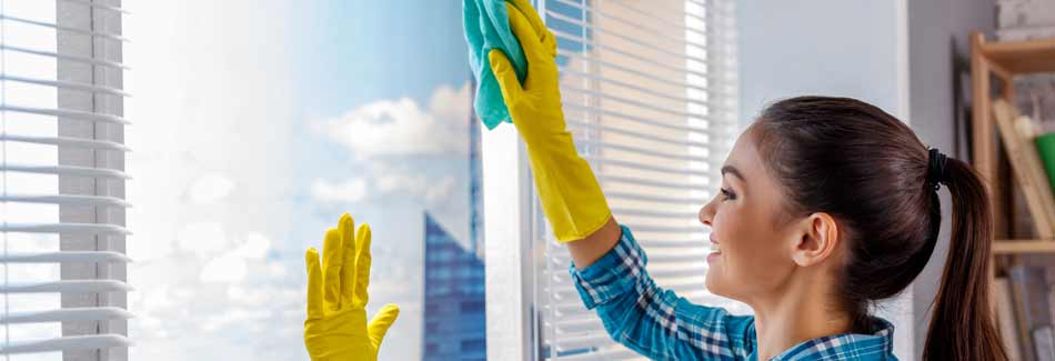 Eine Frau putzt ein Fenster mit einem Tuch