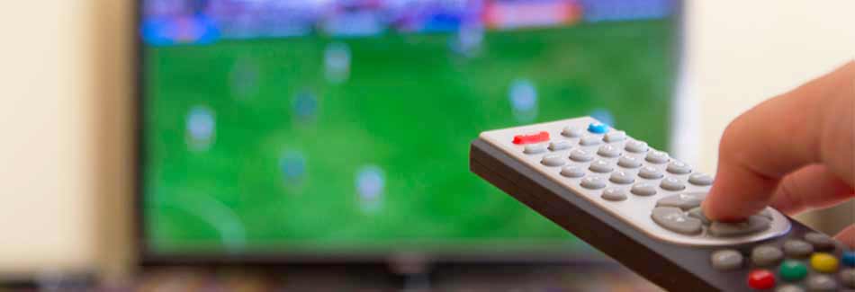 Fernseher kaufen: Jemand richtet eine Fernbedienung auf einen Fernseher