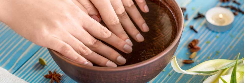 Nagellack schnell trocknen: Eine Frau badet ihre lackierten Nägel in Eiswasser